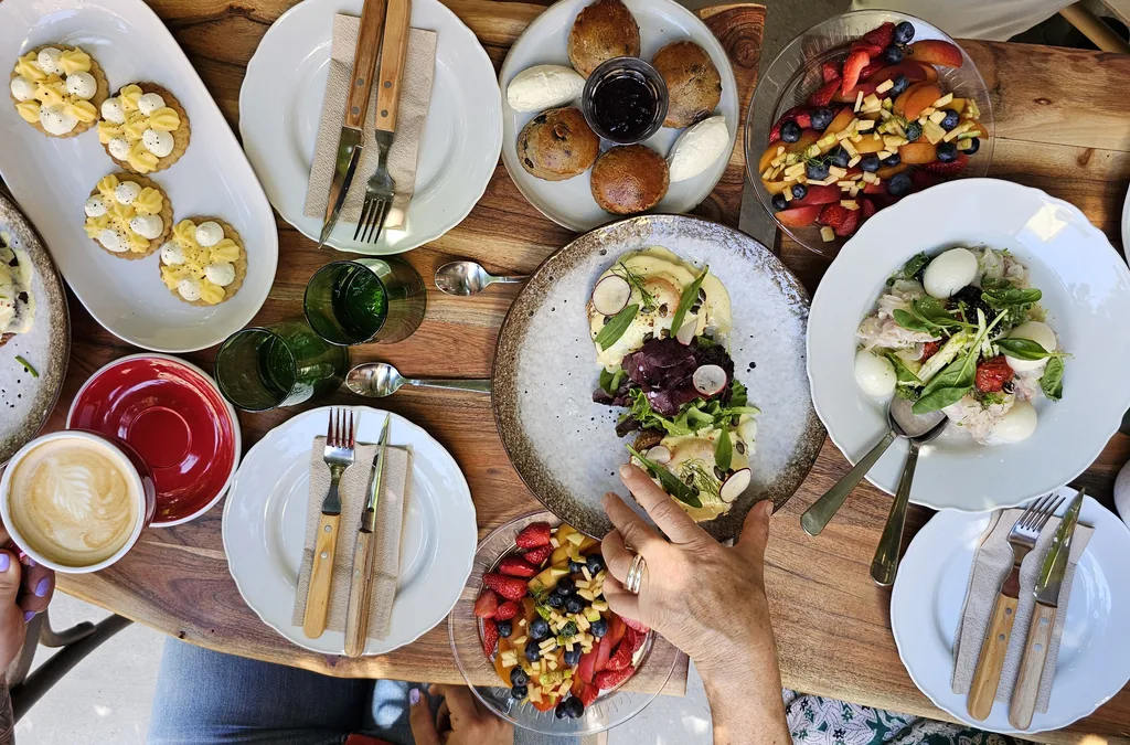 table de brunch avec pleins de jolies assiettes colorées, des cafés et des fruits frais