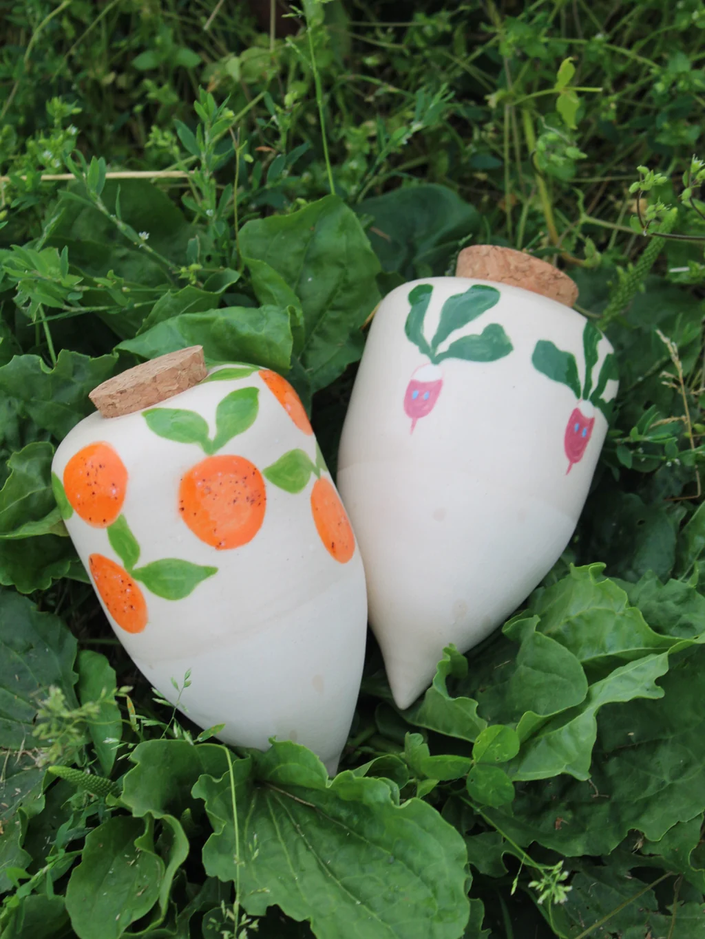 deux olla avec des motifs différents (orange et radis) posé dans l'herbe